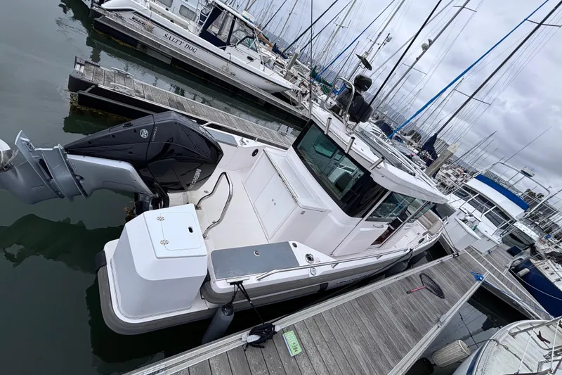 Slide: The Image of 2022 Axopar 28 Cabin boat docked at marina, featuring sleek design and powerful outboard motor. - 4