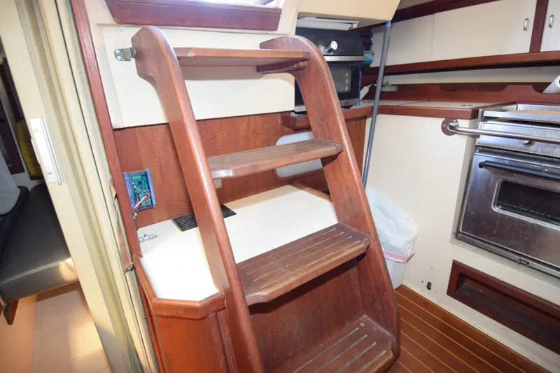 Slide: The Image of Interior of 1989 Catalina 36 sailboat featuring wooden steps and compact kitchen area. - 18