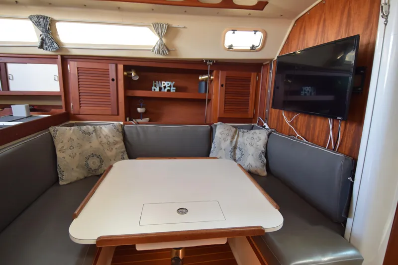 Slide: The Image of 1989 Catalina 36 yacht interior with cozy seating, table, and mounted TV. - 26