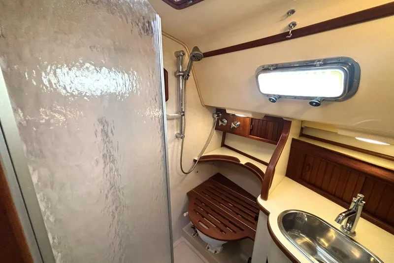 Slide: The Image of 2001 Island Packet 380 yacht bathroom with shower, sink, and wooden accents. - 19