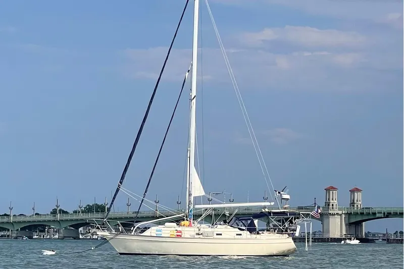 Slide: The Image of Sailboat Island Packet 380, 2001 model, anchored near a bridge on a sunny day. - 49