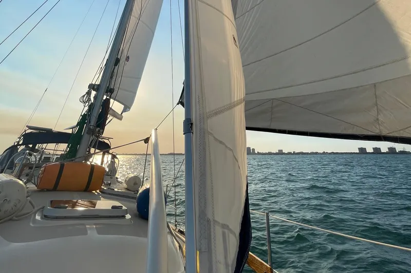 Slide: The Image of Sailing on a 2001 Island Packet 380 yacht at sunset, with city skyline in the distance. - 51