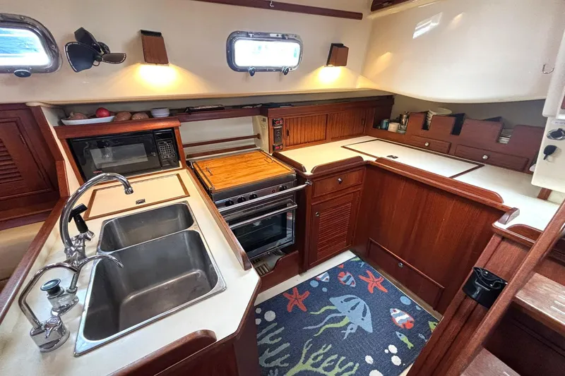 Slide: The Image of 2001 Island Packet 380 yacht kitchen with wood cabinetry, dual sink, and stove. - 7