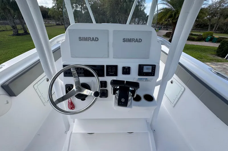 Slide: The Image of 2022 Aquasport 2500 Center Console boat dashboard with Simrad electronics and steering wheel. - 29