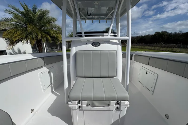 Slide: The Image of 2022 Aquasport 2500 Center Console boat interior with seating, palm tree in background. - 37