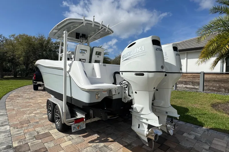 Slide: The Image of 2022 Aquasport 2500 Center Console boat with dual Suzuki engines on a trailer. - 4