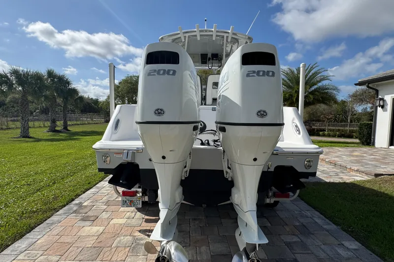 Slide: The Image of 2022 Aquasport 2500 Center Console boat with dual 200 horsepower engines, parked on a driveway. - 6