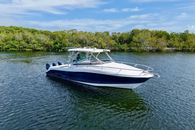 Slide: The Image of 2006 Hydra-Sports Vector 3300 VX boat cruising on a calm lake with lush greenery. - 2