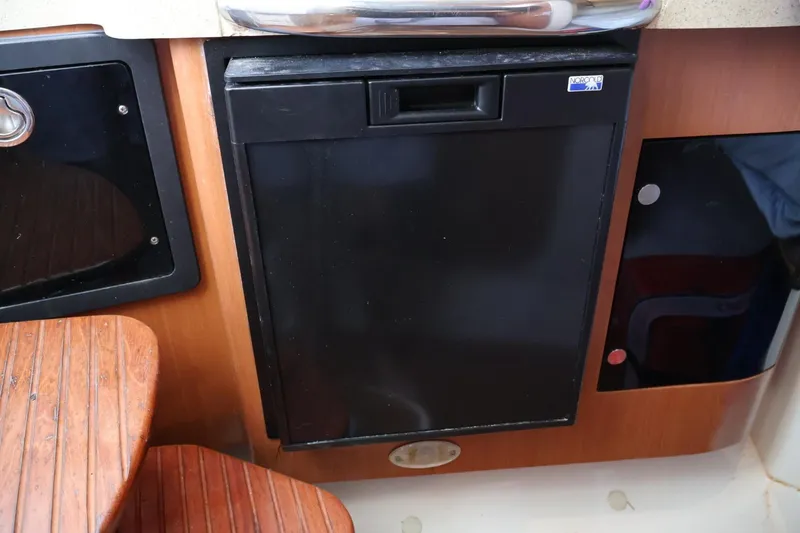 Slide: The Image of 2006 Hydra-Sports Vector 3300 VX interior with compact black refrigerator and wooden cabinetry. - 9