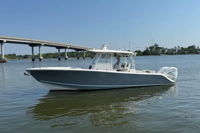 Slide: The Image of 2023 Cobia 350 Center Console boat on calm water near a bridge. - 2