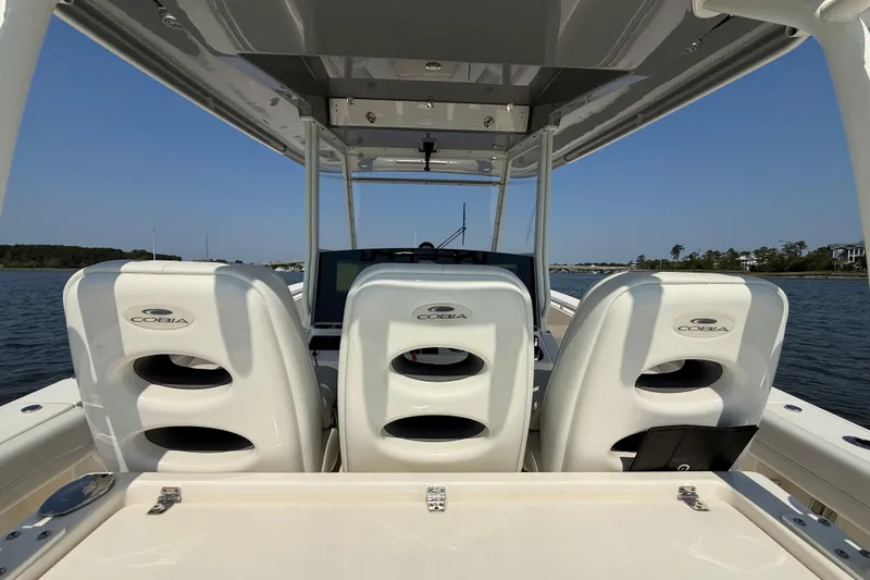 Slide: The Image of 2023 Cobia 350 Center Console boat interior with three white seats on a sunny day. - 25