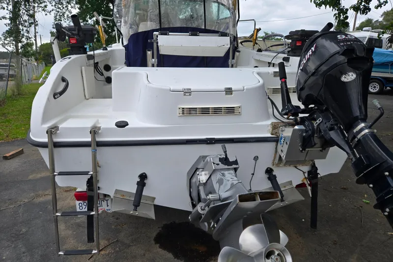 Slide: The Image of 2000 Seaswirl Striper 2300 boat with Mercury outboard motor and ladder, parked outdoors. - 3