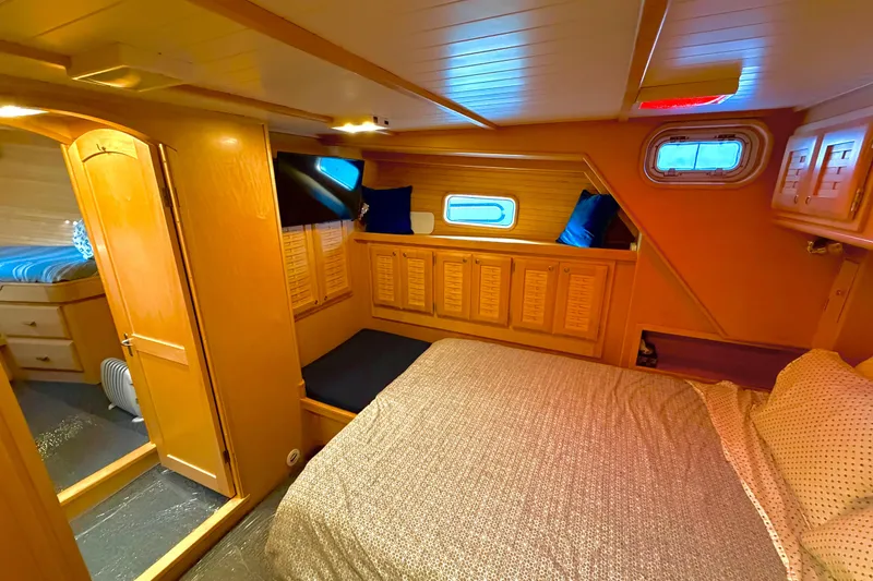 Slide: The Image of Cozy 1998 Waterline Pilothouse interior with wooden cabinetry and comfortable bedding. - 12