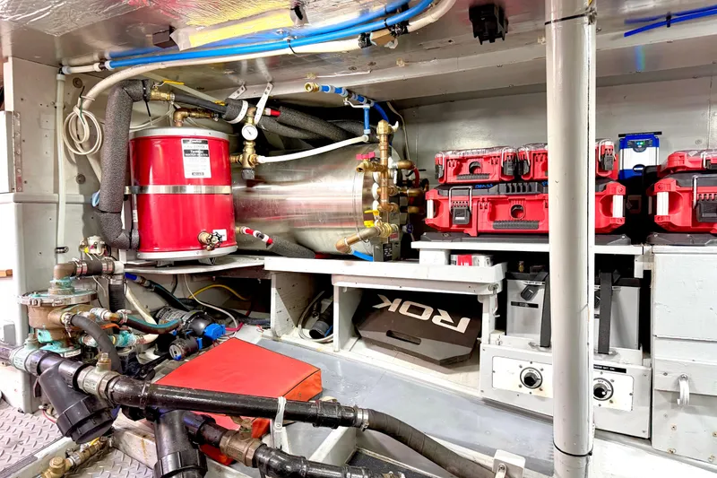 Slide: The Image of Engine room of a 1998 Waterline Pilothouse with red equipment and piping. - 19