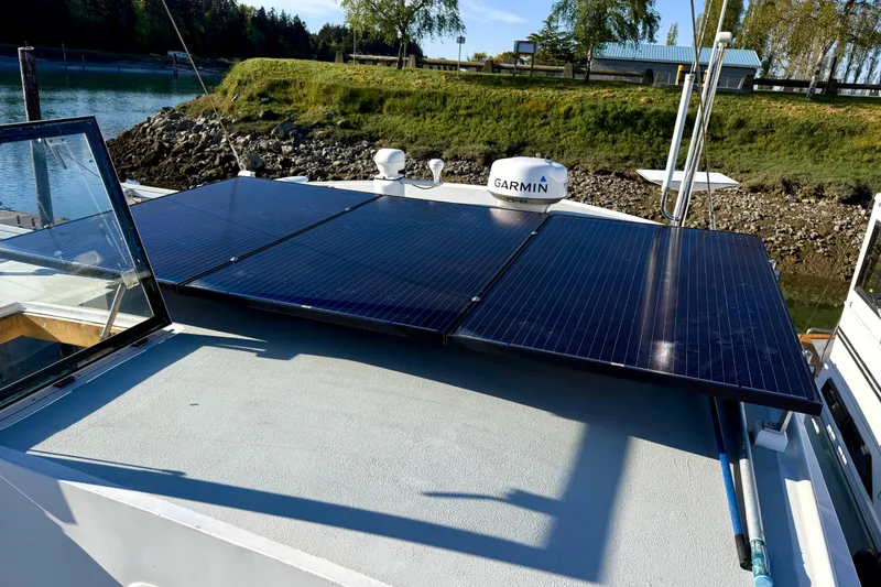 Slide: The Image of Solar panels on a 1998 Waterline Pilothouse boat, docked near a grassy shoreline. - 24