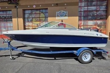 The Image of 2012 Four Winns H180LE boat on trailer, parked outside a building. - 1