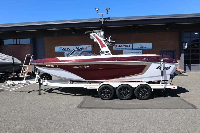 The Image of 2022 Tigé 25ZX boat on trailer, parked outside dealership. - 1