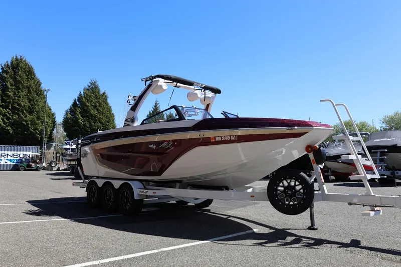 Slide: The Image of 2022 Tigé 25ZX boat on trailer in parking lot under clear blue sky. - 12