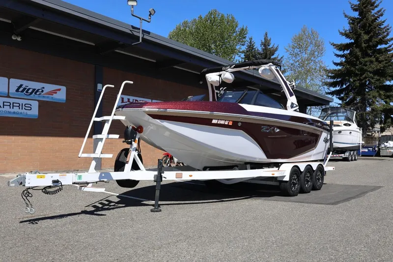 Slide: The Image of 2022 Tigé 25ZX boat on trailer, parked outside dealership under clear blue sky. - 16