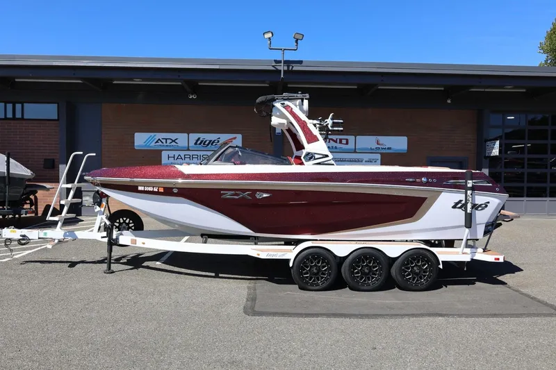 Slide: The Image of 2022 Tigé 25ZX boat on trailer, parked outside dealership, showcasing sleek design. - 17
