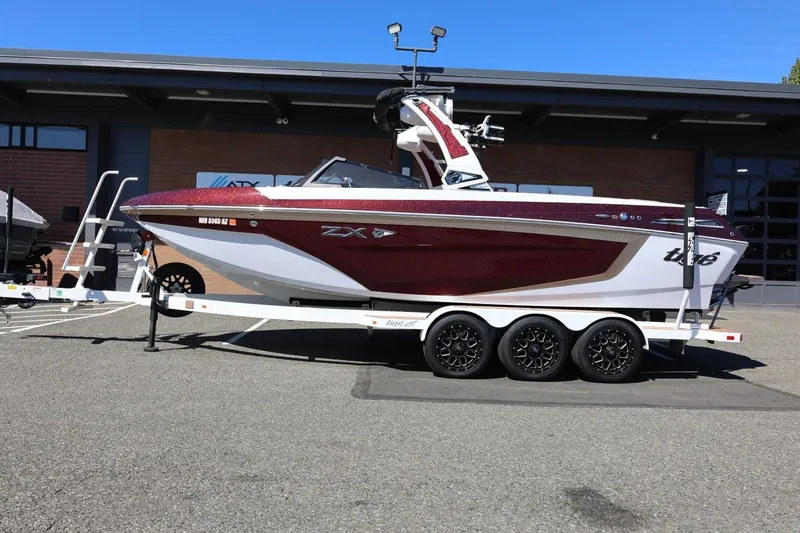 Slide: The Image of 2022 Tigé 25ZX boat on trailer, parked outdoors, showcasing sleek design and modern features. - 18