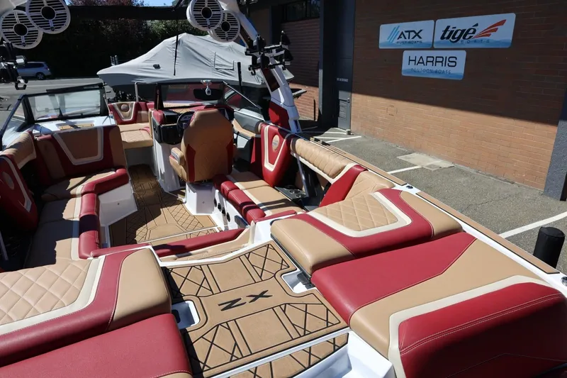 Slide: The Image of 2022 Tigé 25ZX boat interior with red and tan seating, parked outside dealership. - 20