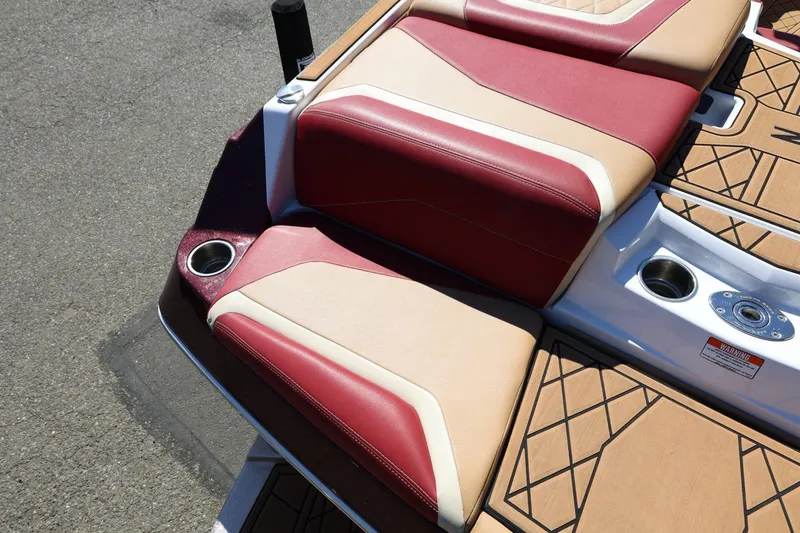 Slide: The Image of 2022 Tigé 25ZX boat with red and beige seating, cup holders, and teak flooring. - 22
