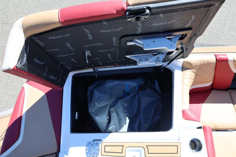 Slide: The Image of Open storage compartment in 2022 Tigé 25ZX boat with red and beige seating. - 27