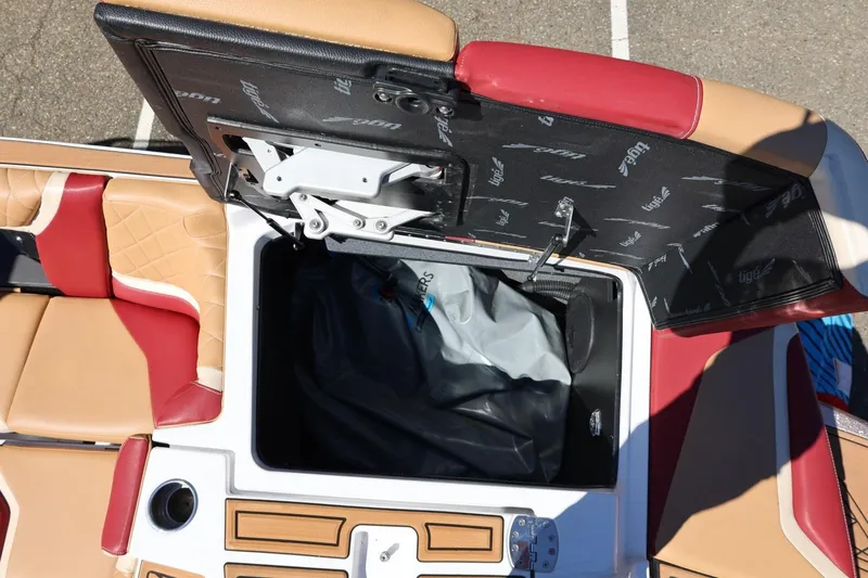 Slide: The Image of 2022 Tigé 25ZX boat interior storage compartment with red and tan seating. - 28