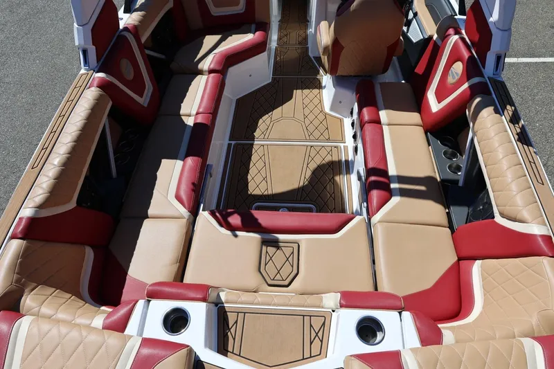 Slide: The Image of 2022 Tigé 25ZX boat interior with tan and red seating, cup holders, and diamond-patterned flooring. - 30