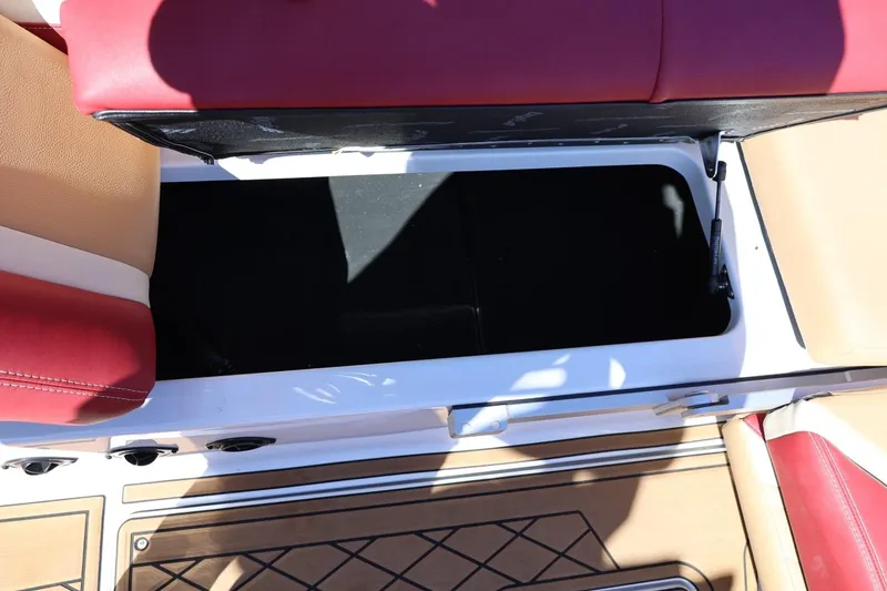 Slide: The Image of 2022 Tigé 25ZX boat interior storage compartment with red and beige seating. - 38