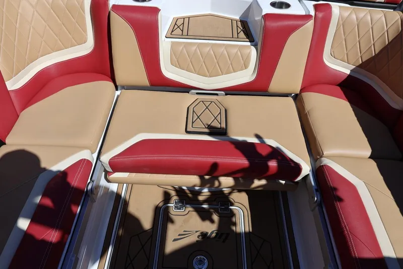 Slide: The Image of 2022 Tigé 25ZX boat interior with red and tan seating, diamond stitching, and cup holders. - 42