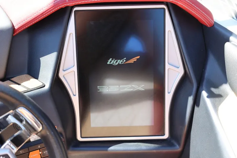 Slide: The Image of 2022 Tigé 25ZX boat dashboard with touchscreen display and red leather accents. - 52