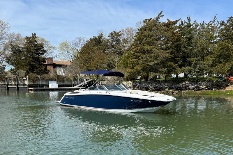 The Image of 2015 Cobalt 26SD boat on calm water near a wooded shoreline. - 0