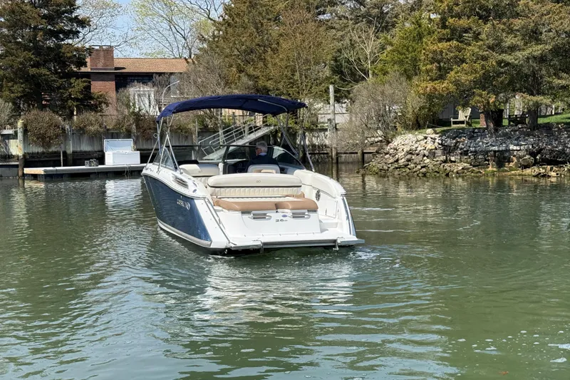 Slide: The Image of 2015 Cobalt 26SD boat cruising on a calm lake near a wooded shoreline. - 2