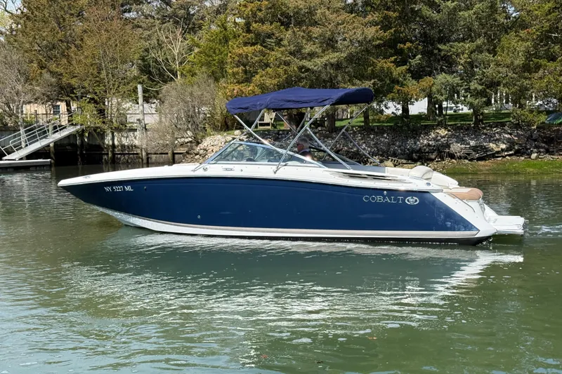Slide: The Image of 2015 Cobalt 26SD boat with blue hull and canopy on a calm river. - 4