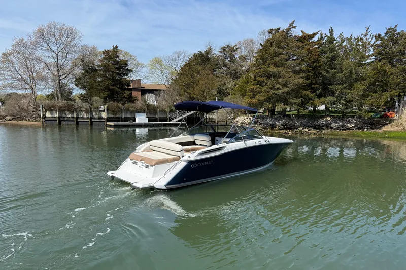 Slide: The Image of 2015 Cobalt 26SD boat cruising on a serene lake with trees in the background. - 5