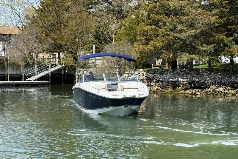 Slide: The Image of 2015 Cobalt 26SD boat cruising on a serene lake with lush greenery. - 6