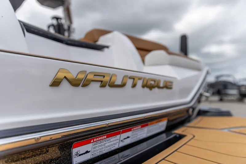Slide: The Image of 2025 Nautique Super Air Nautique G23 boat with gold logo, close-up view. - 20
