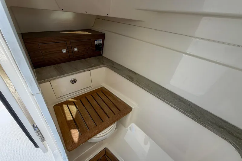 Slide: The Image of 2017 Boston Whaler 320 Vantage cabin interior with wooden accents and storage. - 14