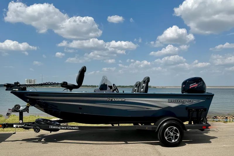 Slide: The Image of 2026 Ranger VS1682SC Angler boat by a lake under a blue sky with clouds. - 14