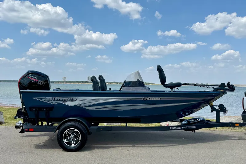 Slide: The Image of 2026 Ranger VS1682SC Angler boat on trailer by a lake under a blue sky. - 2