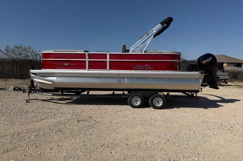 The Image of 2026 Sun Tracker Party Barge 22 DLX pontoon boat on trailer, parked outdoors. - 0