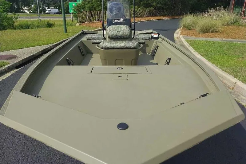 Slide: The Image of 2026 Tracker Grizzly 1860 CC boat with camouflage seating, parked on pavement. - 3