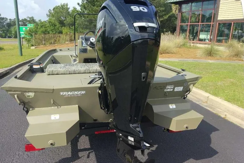 Slide: The Image of 2026 Tracker Grizzly 1860 CC boat with powerful outboard motor, parked outdoors. - 7