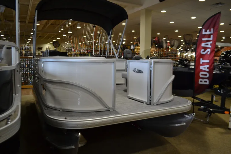 Slide: The Image of 2026 Sun Tracker Party Barge 16 DLX pontoon boat on display at indoor boat sale. - 2