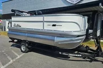 Slide: The Image of 2026 Sun Tracker Party Barge 16 DLX pontoon boat on trailer, parked outdoors. - 2