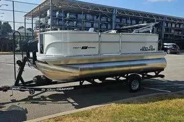 The Image of 2026 Sun Tracker Party Barge 16 DLX pontoon boat on trailer in parking lot. - 0