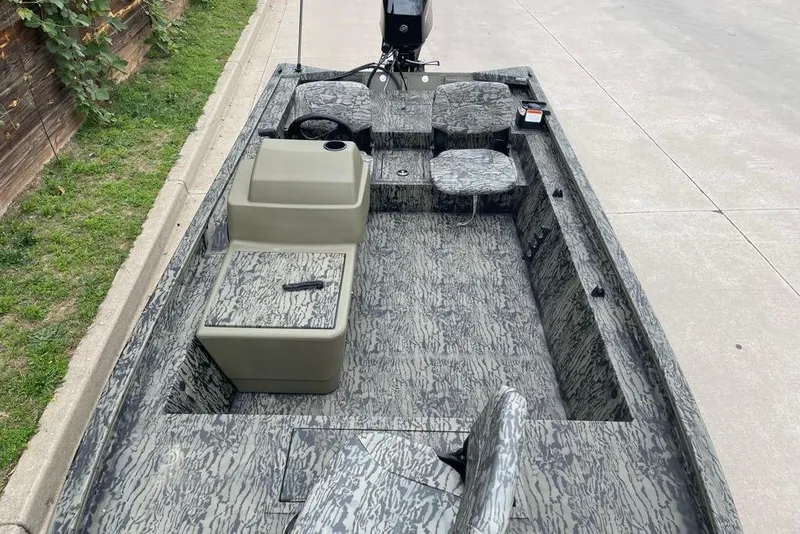 Slide: The Image of 2026 Tracker Grizzly 1754 SC boat with camouflage interior, parked on concrete. - 2