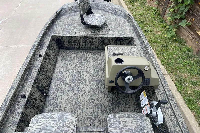 Slide: The Image of 2026 Tracker Grizzly 1754 SC boat interior with camouflage design and steering console. - 3